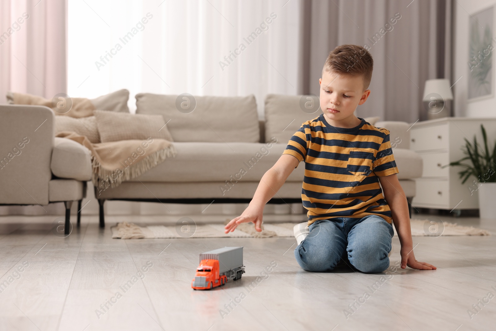 Photo of Little boy playing with toy car at home. Space for text