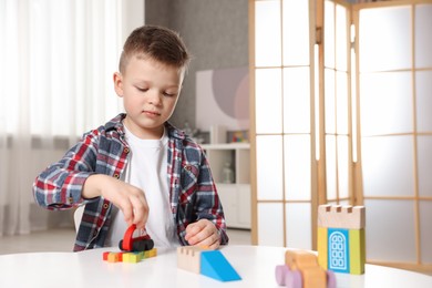 Photo of Little boy playing with toys at table indoors