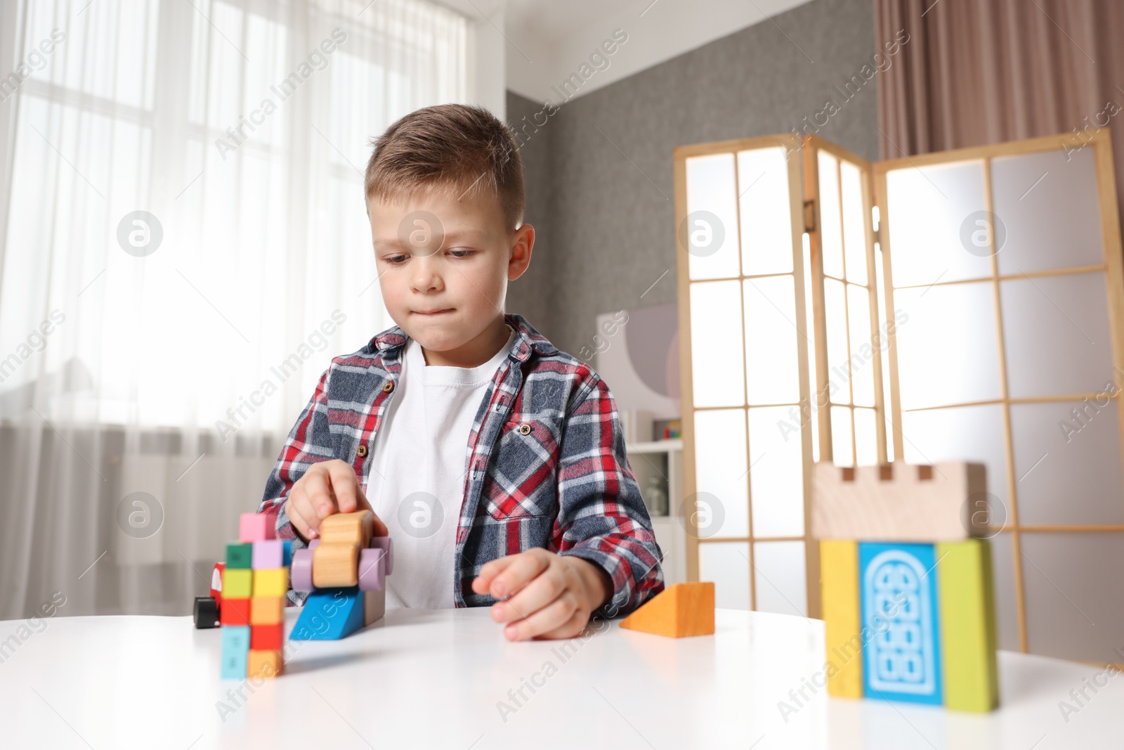 Photo of Little boy playing with toys at table indoors