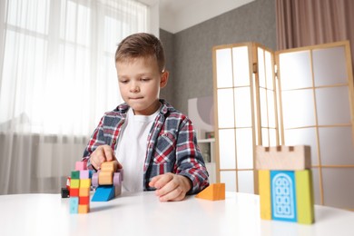 Little boy playing with toys at table indoors