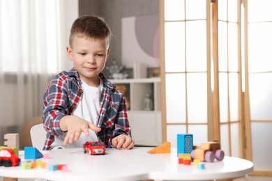 Photo of Little boy playing with toys at table indoors