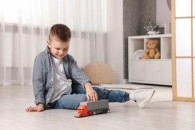 Photo of Little boy playing with toy car at home. Space for text