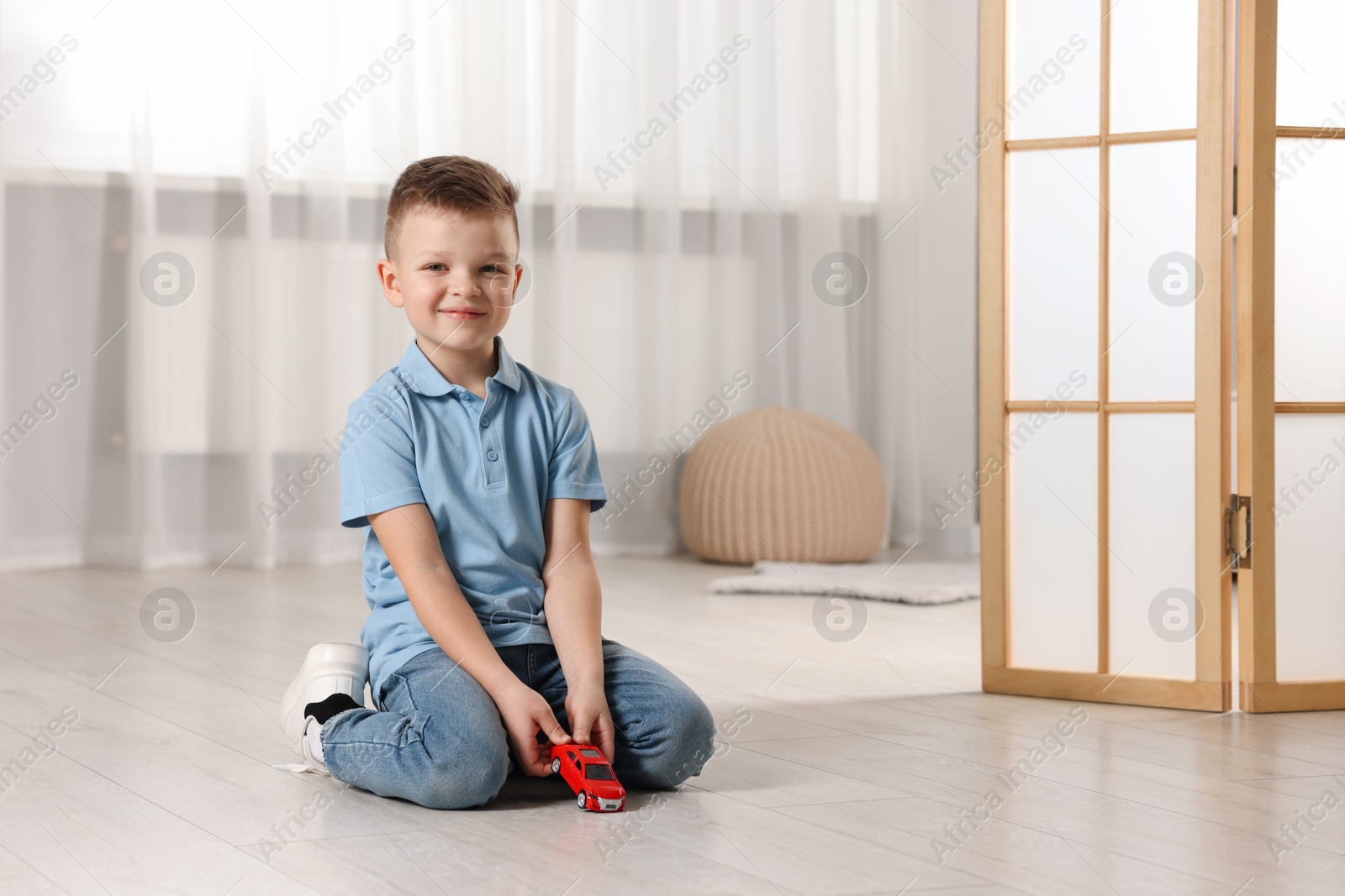 Photo of Little boy playing with toy car at home. Space for text