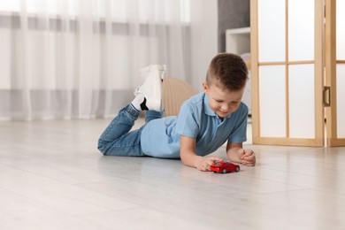 Photo of Little boy playing with toy car at home