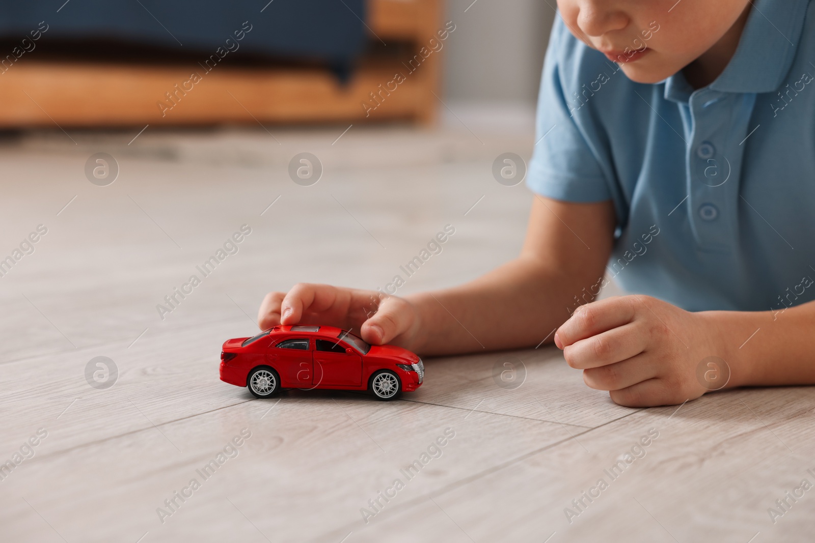 Photo of Little boy playing with toy car at home, closeup. Space for text