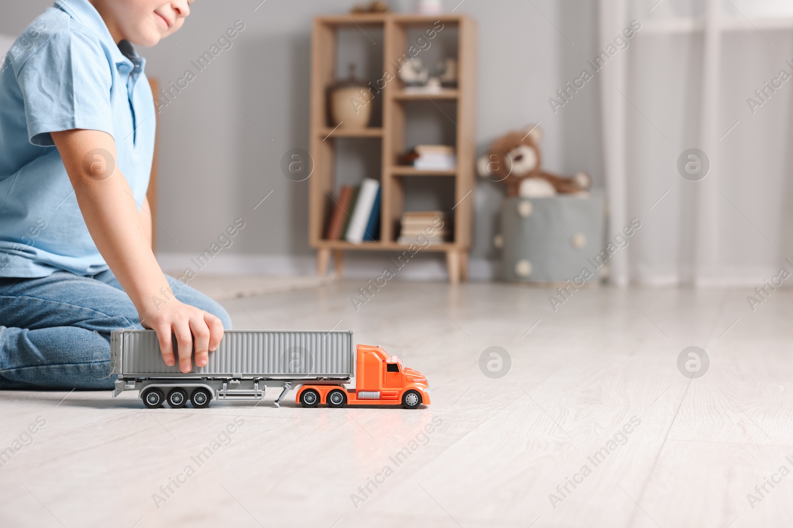 Photo of Little boy playing with toy car at home, closeup. Space for text