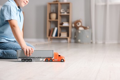 Little boy playing with toy car at home, closeup. Space for text