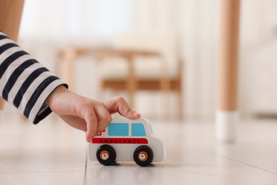 Photo of Little girl playing with toy car on floor at home, closeup. Space for text