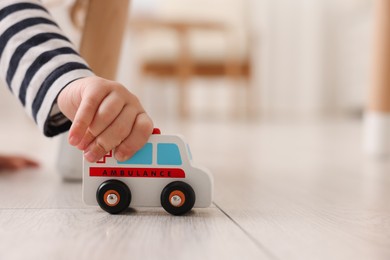 Little girl playing with toy car on floor at home, closeup. Space for text