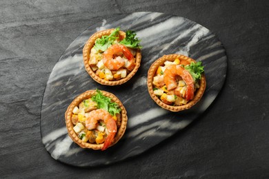 Photo of Tartlets with delicious filling on black table, top view