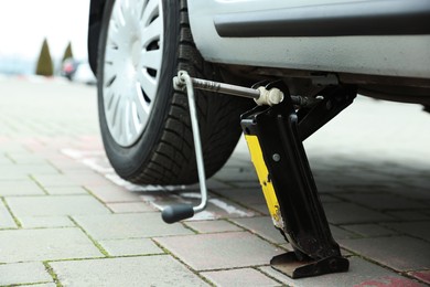 Photo of Car lifted by scissor jack on roadside outdoors