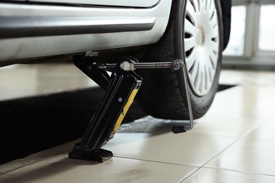 Photo of Car lifted by scissor jack at service station