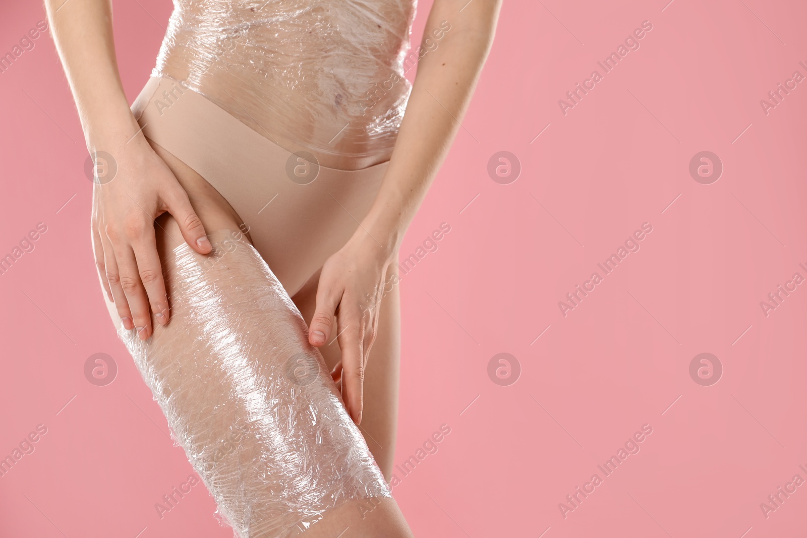 Photo of Woman doing spa body wraps on pink background, closeup. Space for text