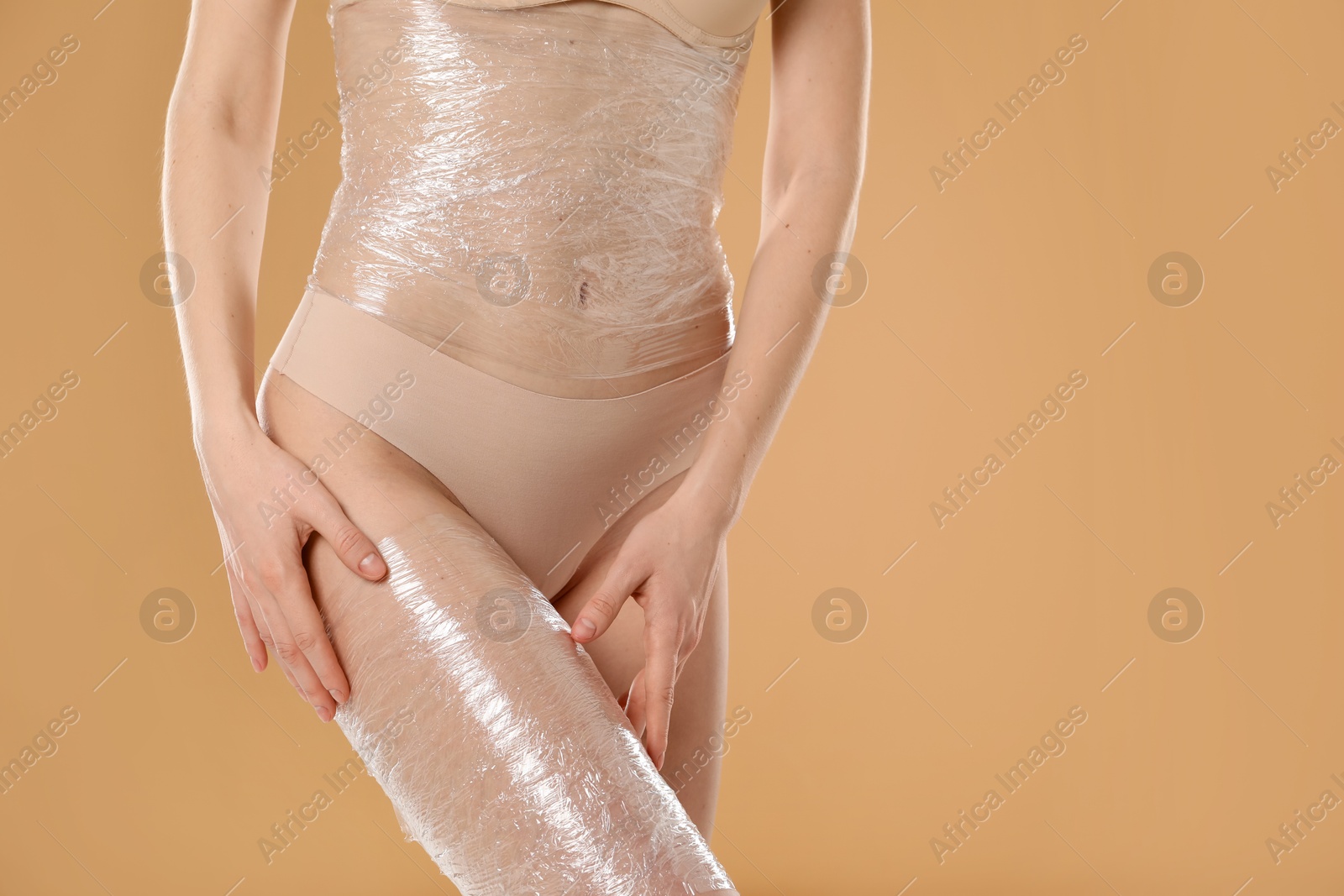 Photo of Woman doing spa body wraps on beige background, closeup. Space for text