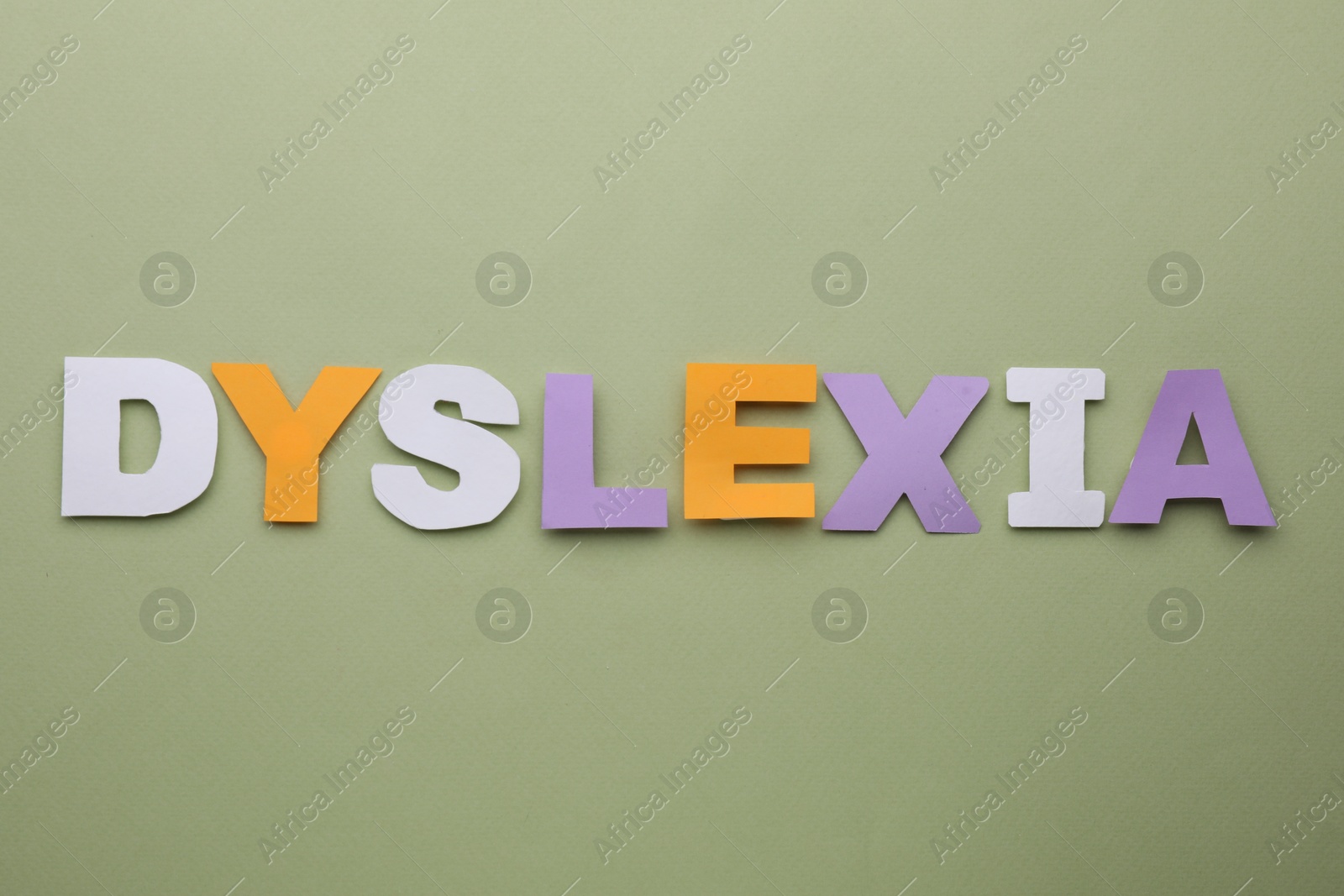 Photo of Word Dyslexia made of paper letters on olive background, flat lay