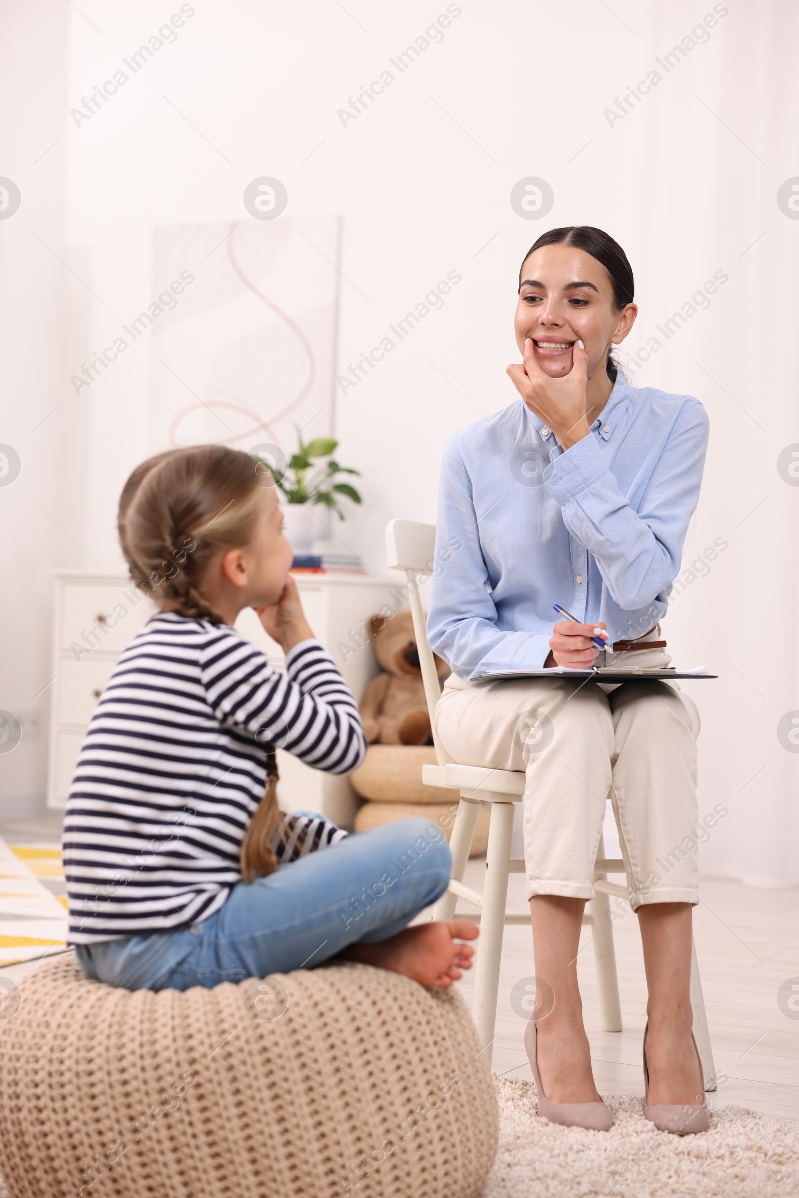 Photo of Dyslexia treatment. Speech therapist working with girl in room