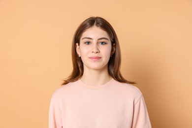 Portrait of beautiful teenage girl on beige background