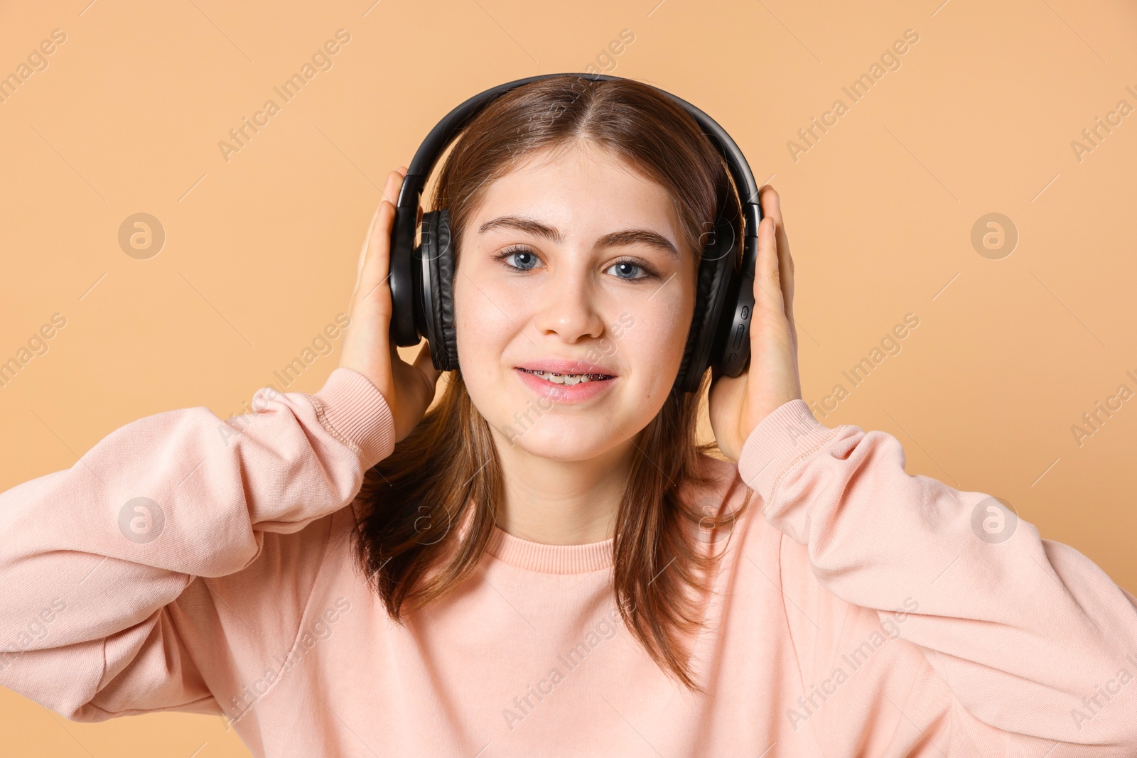 Photo of Portrait of teenage girl in headphones listening to music on beige background