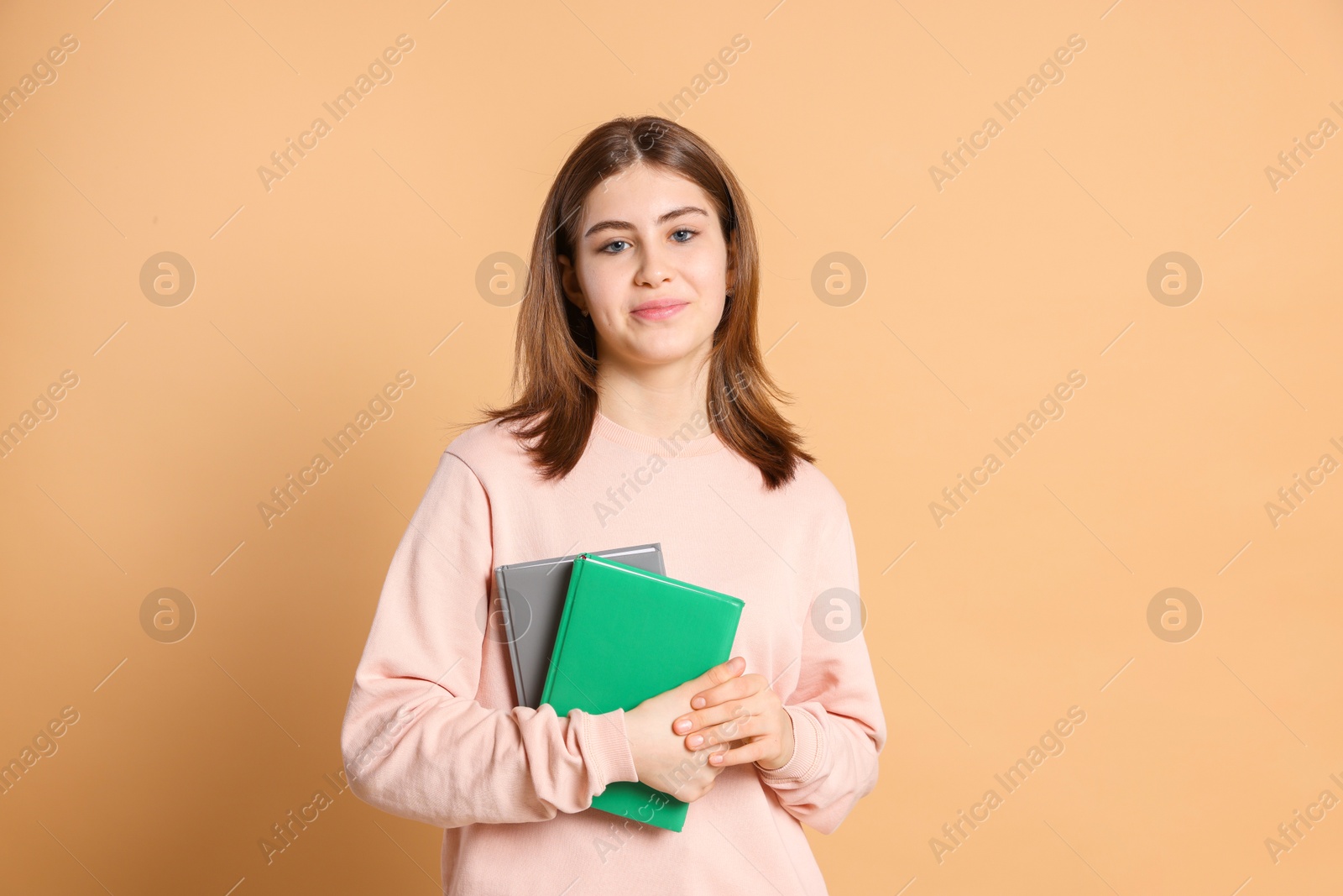 Photo of Portrait of teenage girl with books on beige background