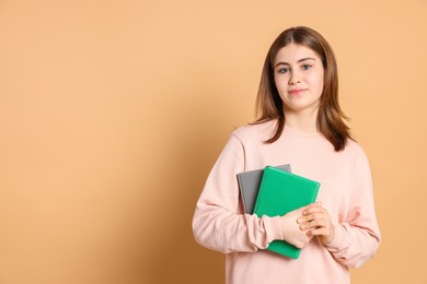 Portrait of teenage girl with books on beige background. Space for text