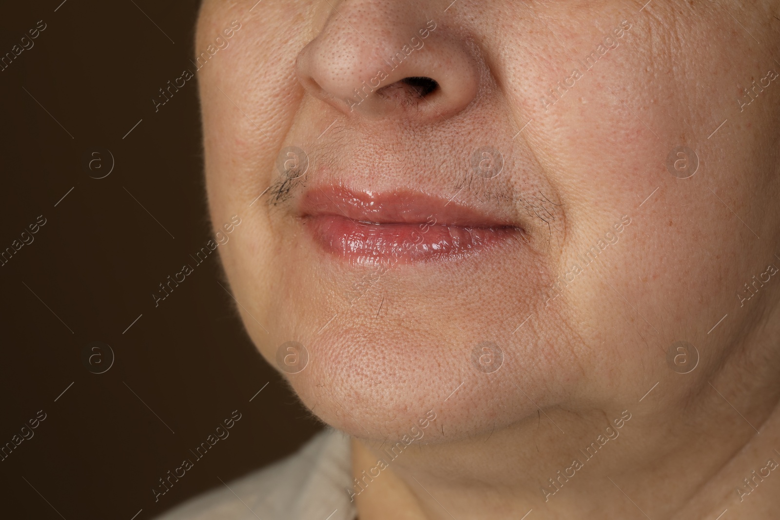 Photo of Senior woman with mustache on brown background, closeup