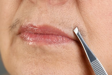 Senior woman plucking her mustache with tweezers, closeup