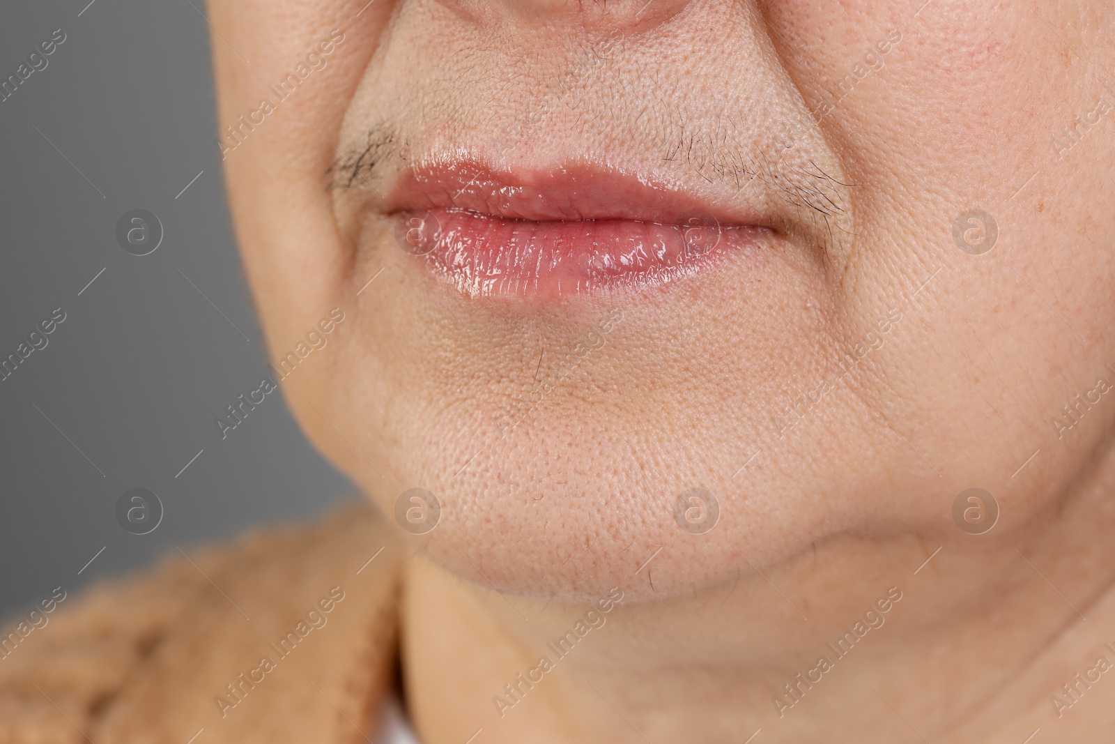 Photo of Senior woman with mustache on grey background, closeup