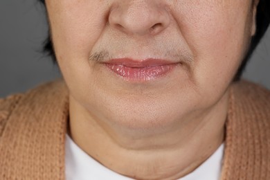 Senior woman with mustache on grey background, closeup