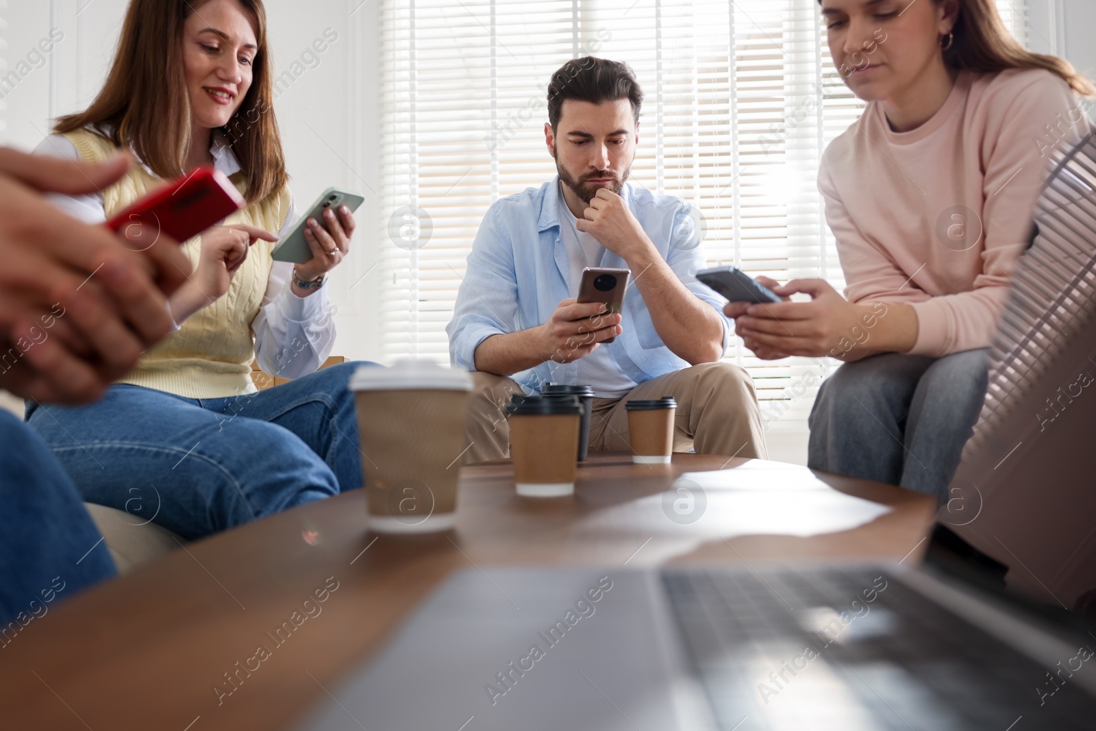 Photo of Internet addiction. Group of friends with gadgets and coffee at table indoors