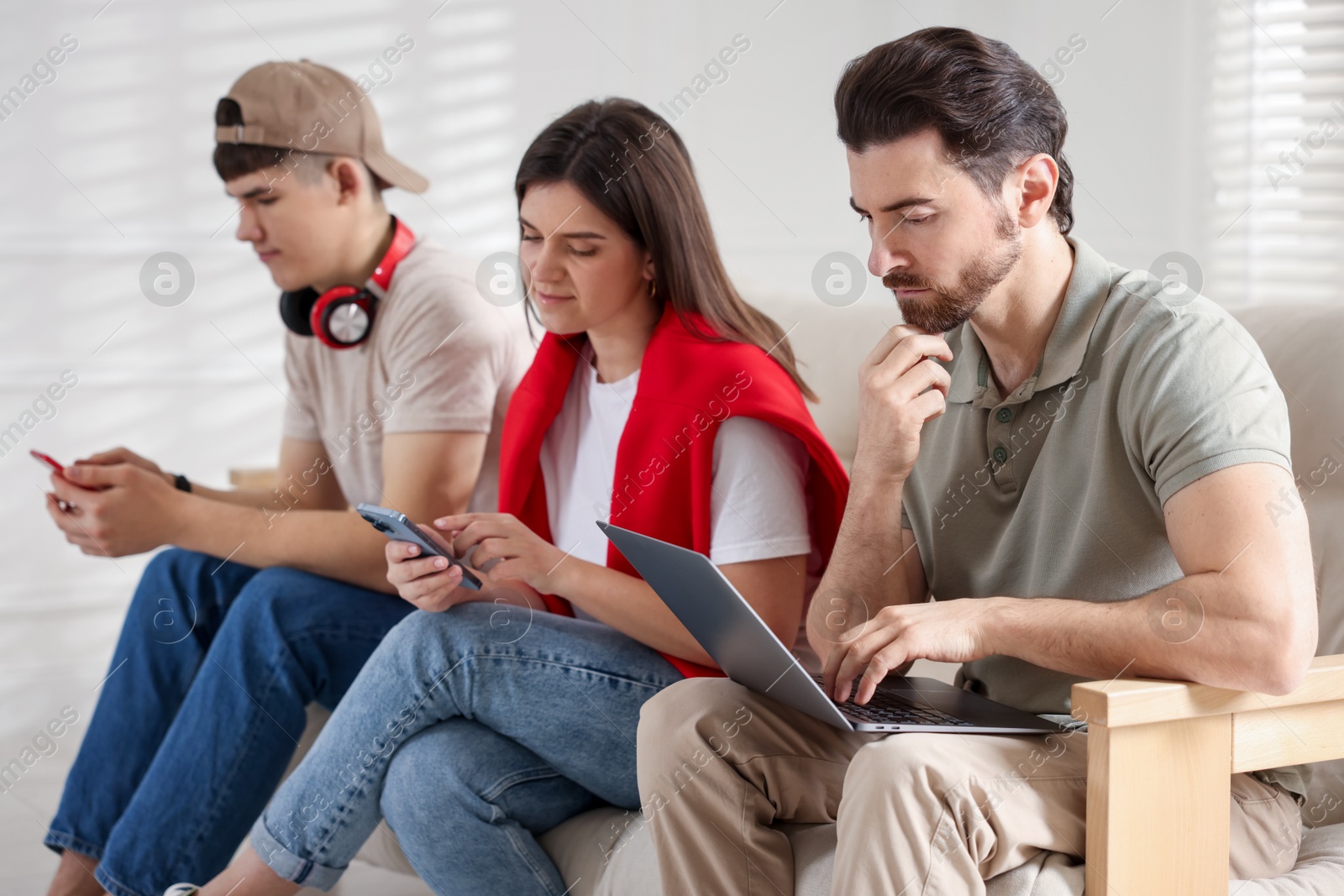 Photo of Internet addiction. Group of people with gadgets on sofa indoors