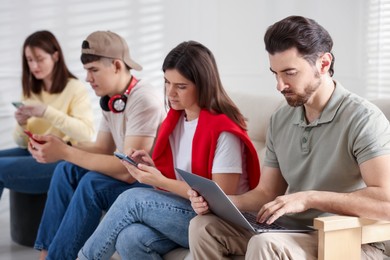 Internet addiction. Group of people with gadgets on sofa indoors