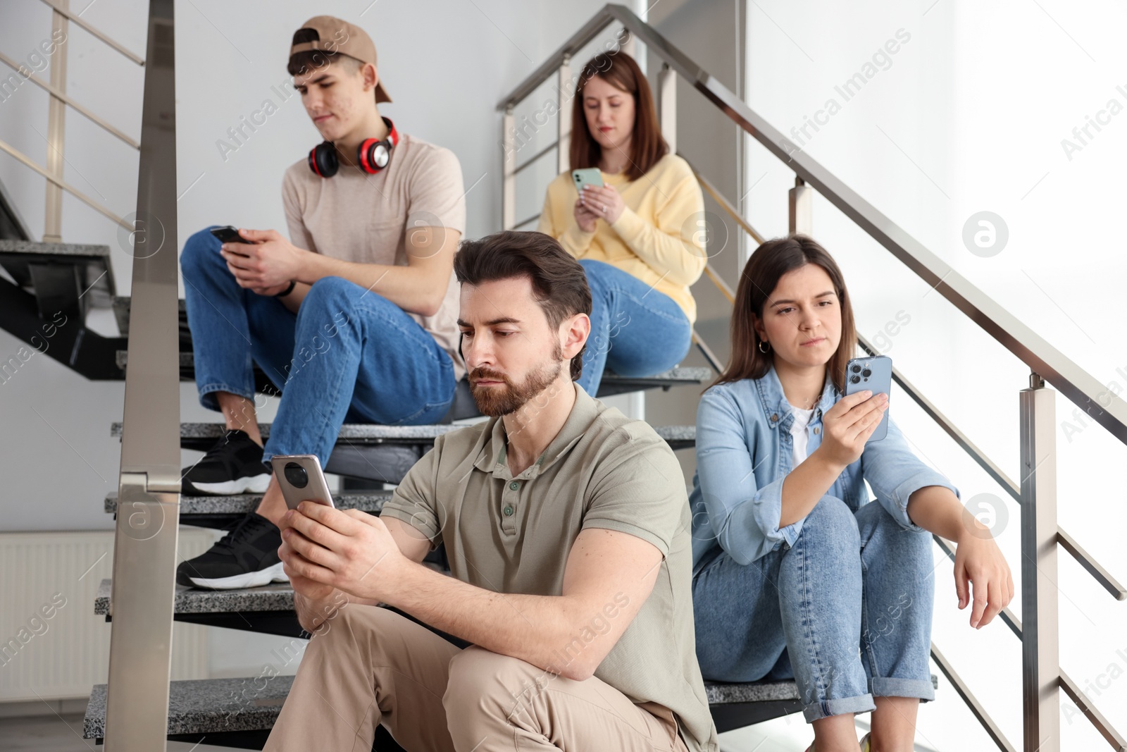 Photo of Internet addiction. Group of people with smartphones on stairs indoors