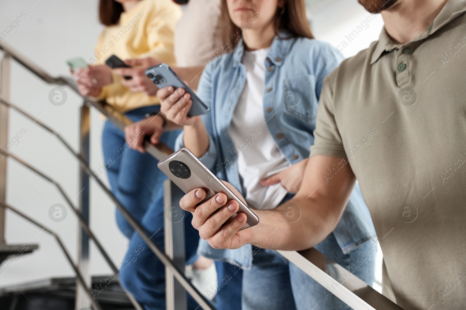 Photo of Internet addiction. Group of people with smartphones on stairs indoors, closeup