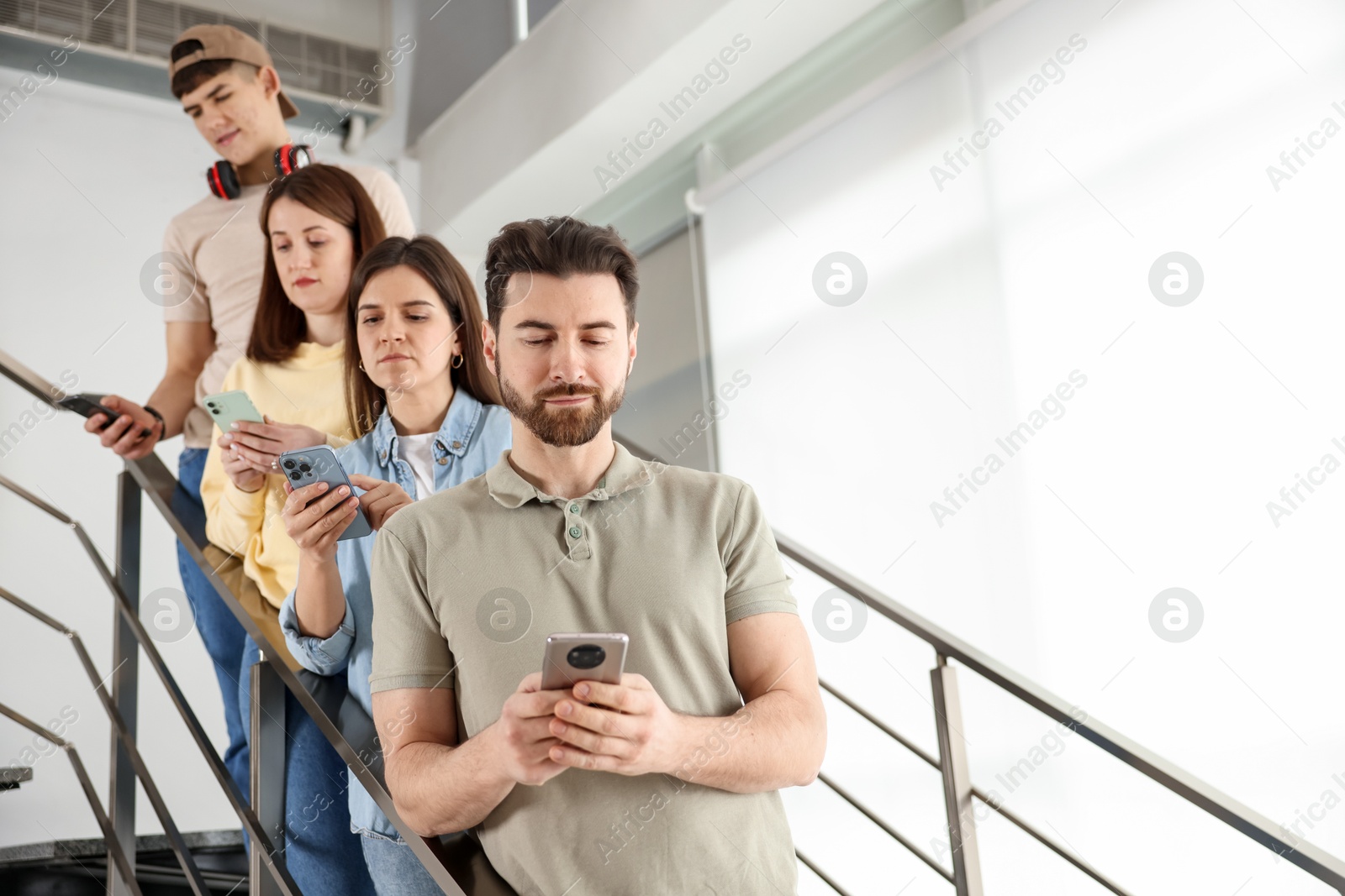 Photo of Internet addiction. Group of people with smartphones on stairs indoors