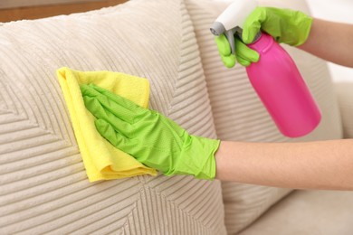 Janitor cleaning sofa with rag at home, closeup