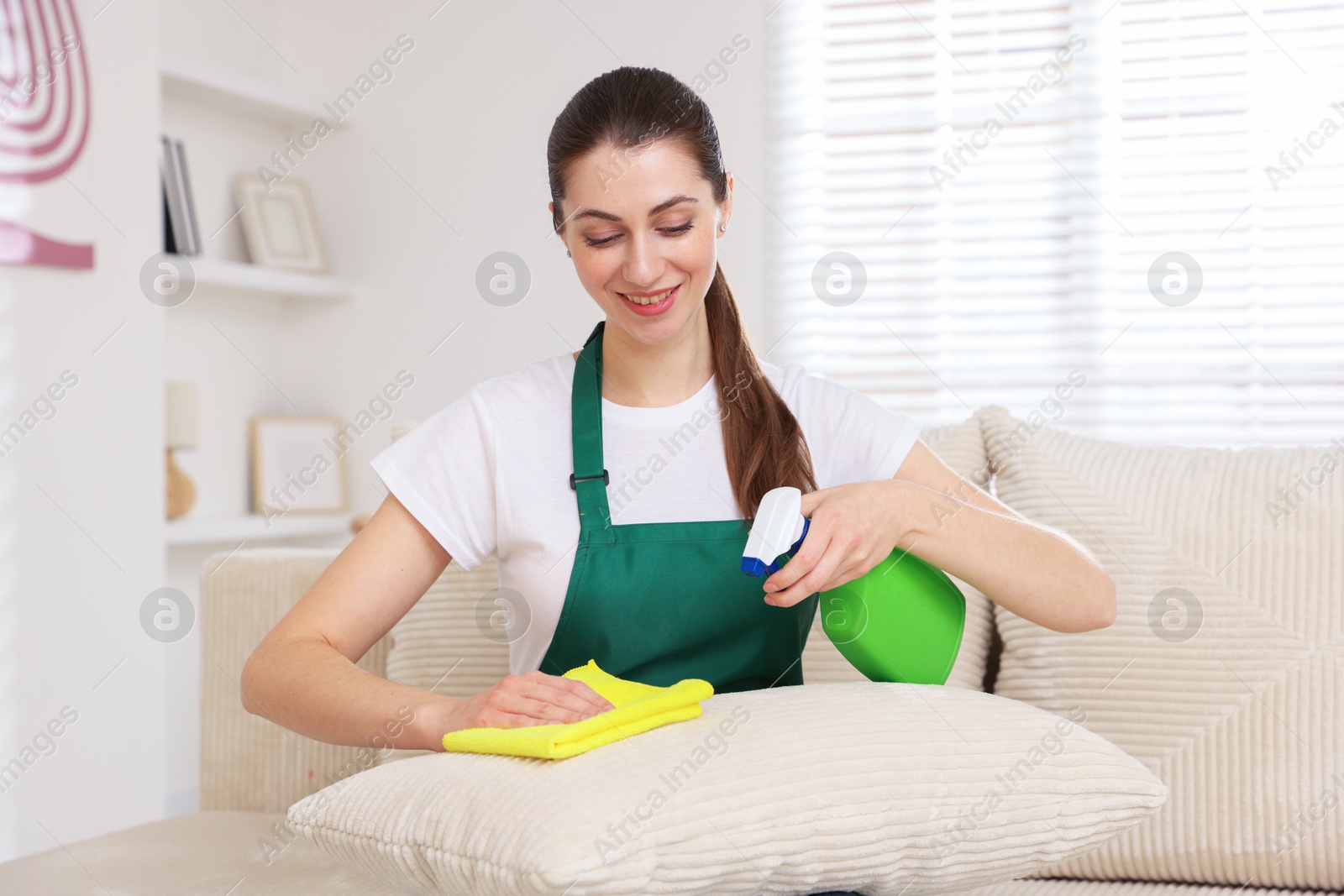 Photo of Janitor cleaning sofa with rag at home