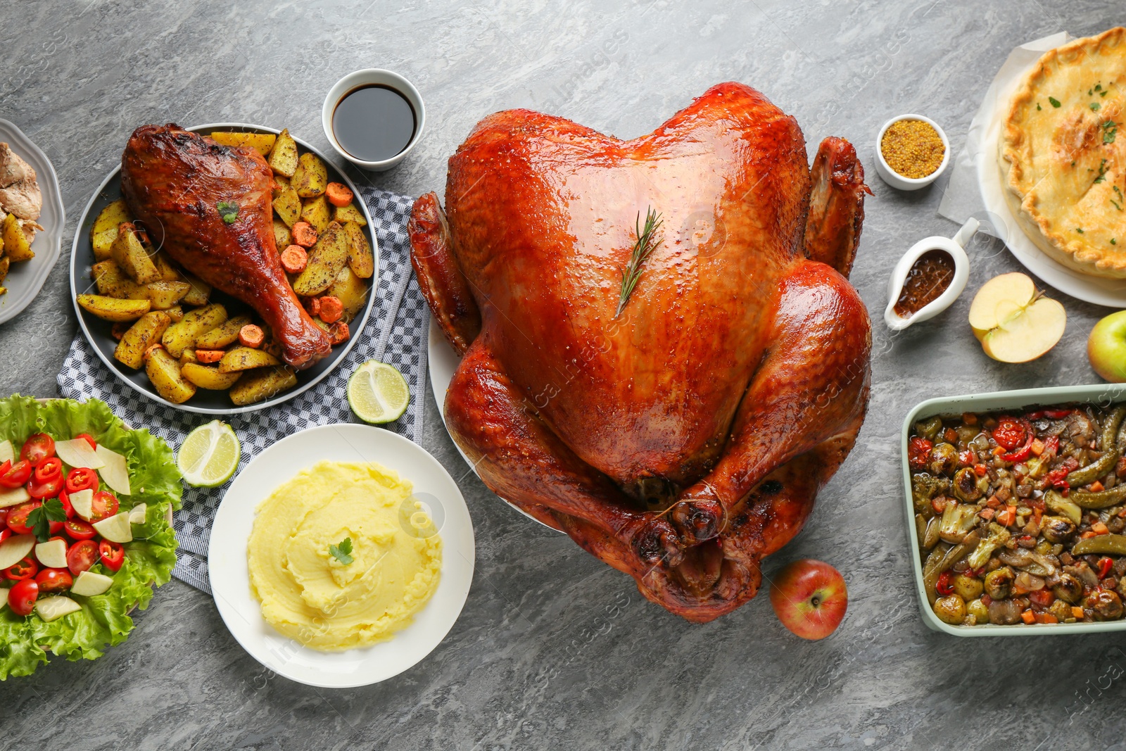 Photo of Whole baked turkey and other dishes served on grey table, flat lay