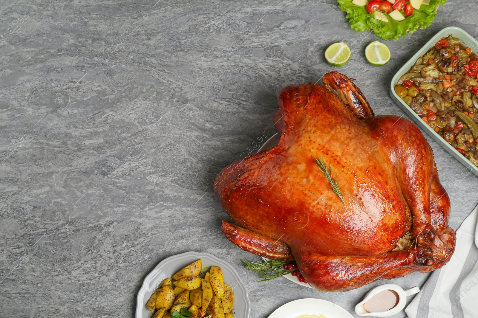 Photo of Whole baked turkey and other dishes served on grey table, flat lay. Space for text