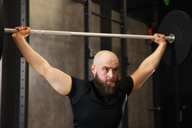 Photo of Sportsman with barbell during crossfit workout in gym