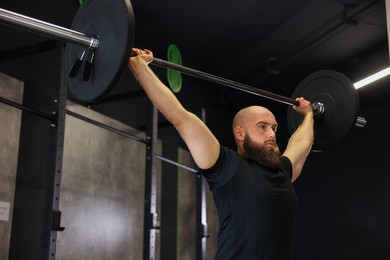 Photo of Sportsman with barbell during crossfit workout in gym