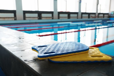 Two kickboards on edge of swimming pool indoors, closeup