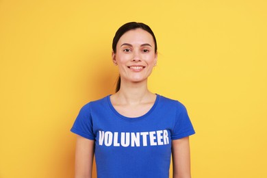 Young beautiful volunteer wearing t-shirt with printed word on orange background