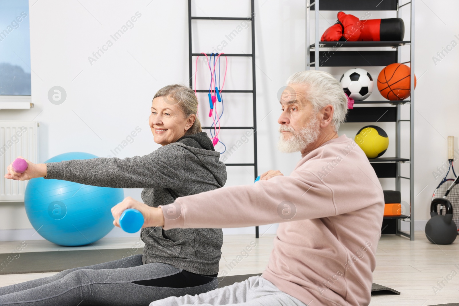 Photo of Elderly couple exercising with dumbbells at home