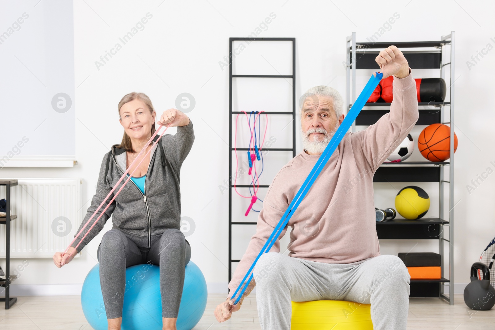 Photo of Elderly couple exercising with elastic bands and fitness balls at home