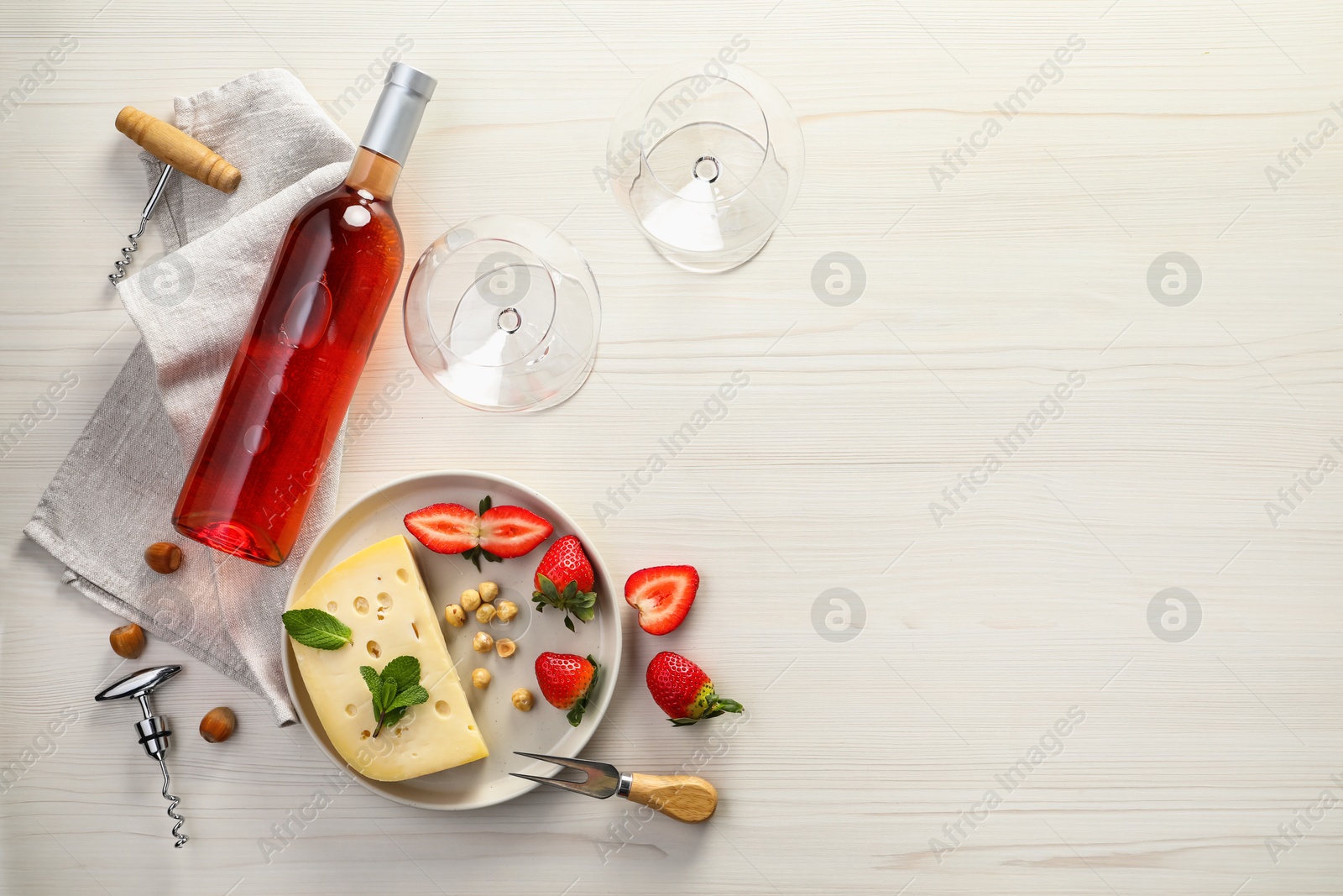 Photo of Flat lay composition with tasty rose wine and different food on light wooden table. Space for text