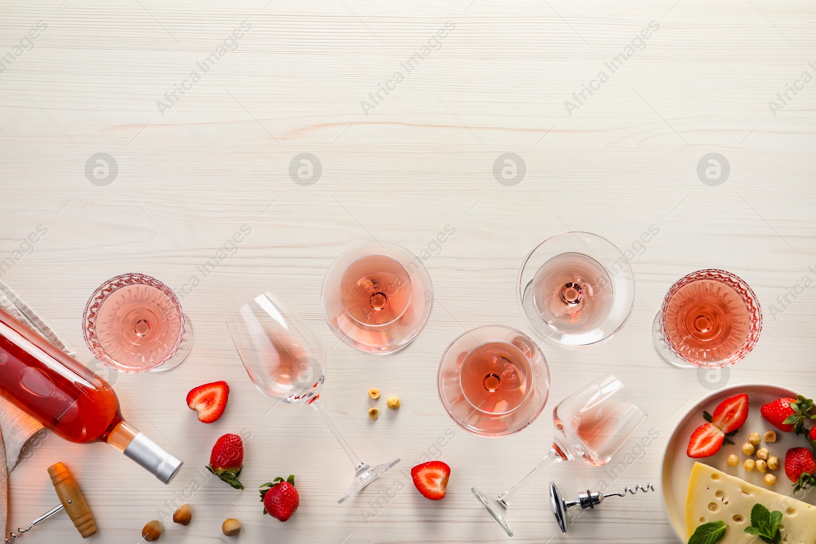 Photo of Flat lay composition with tasty rose wine and different food on light wooden table. Space for text