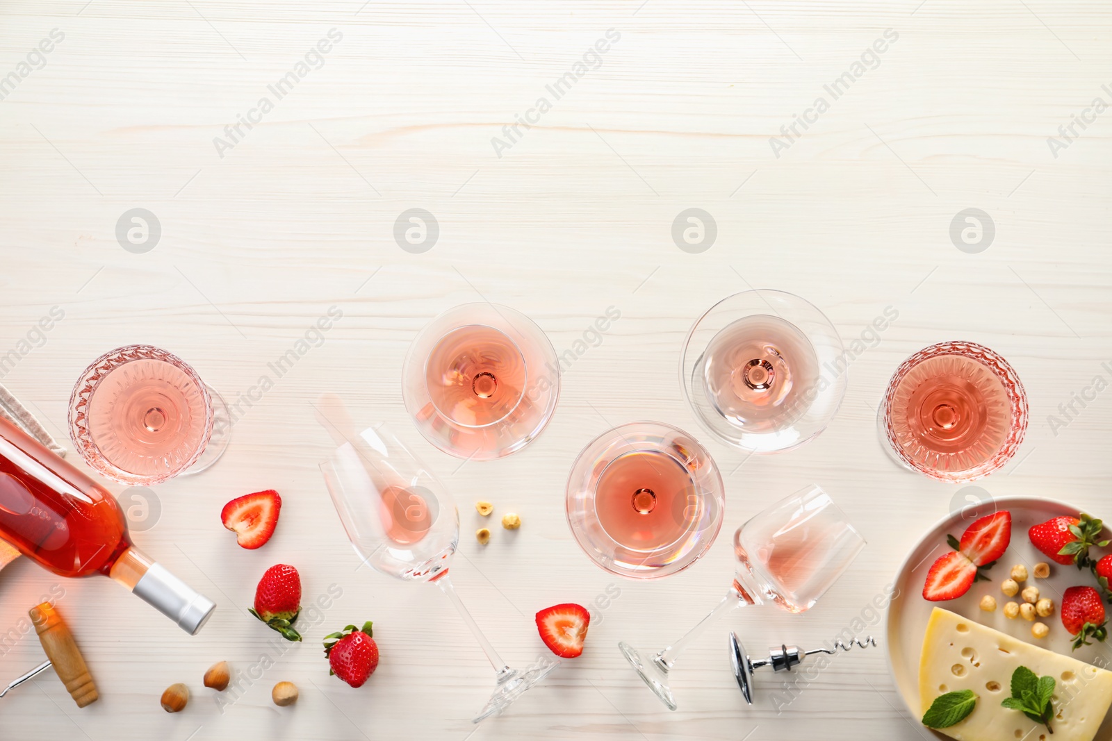 Photo of Flat lay composition with tasty rose wine and different food on light wooden table. Space for text