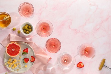 Photo of Flat lay composition with tasty rose wine and different food on pink marble table. Space for text