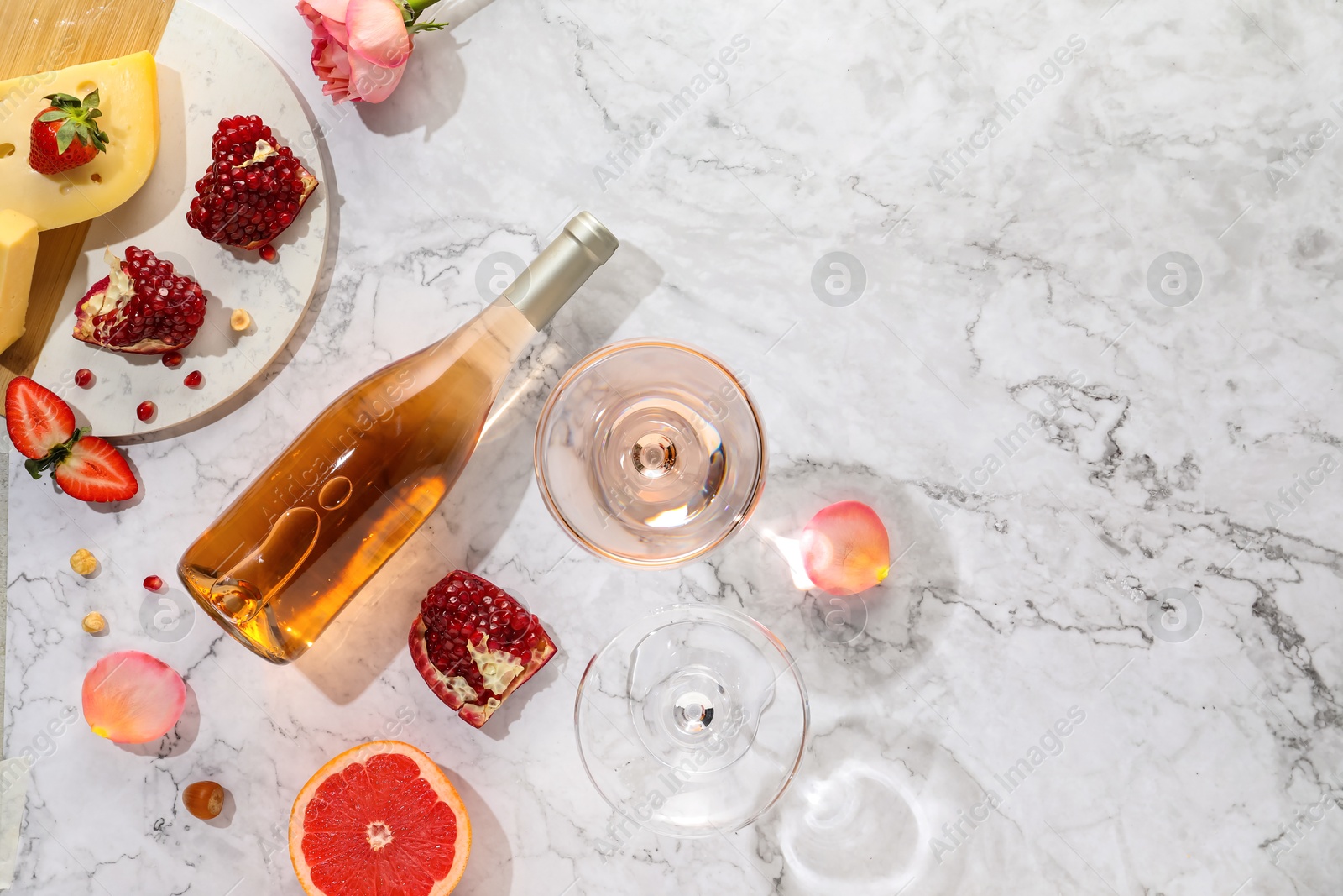 Photo of Flat lay composition with tasty rose wine and snacks on white marble table. Space for text