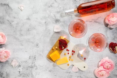 Flat lay composition with tasty rose wine and snacks on light textured table. Space for text